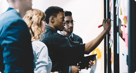 Coworkers writing ideas on a board